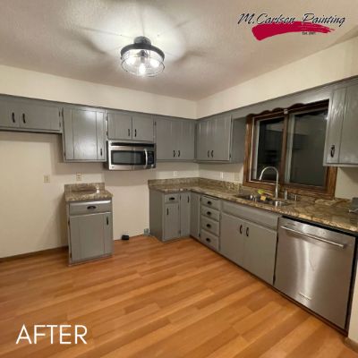 Kitchen after cabinet refinishing in slate gray, with granite countertops and a wood floor