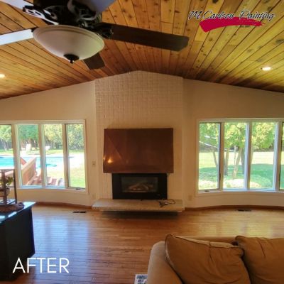Long Lake living room after painting, white brick fireplace below a knotty pine ceiling
