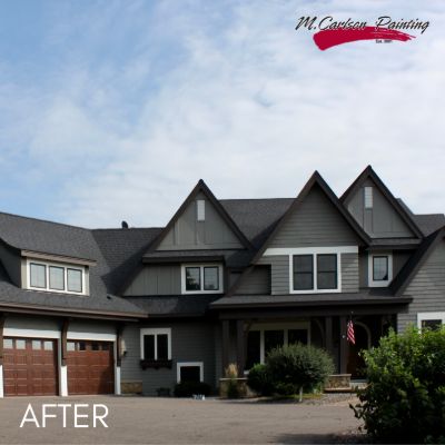 Large house in charcoal siding with steep gables and brown garage doors