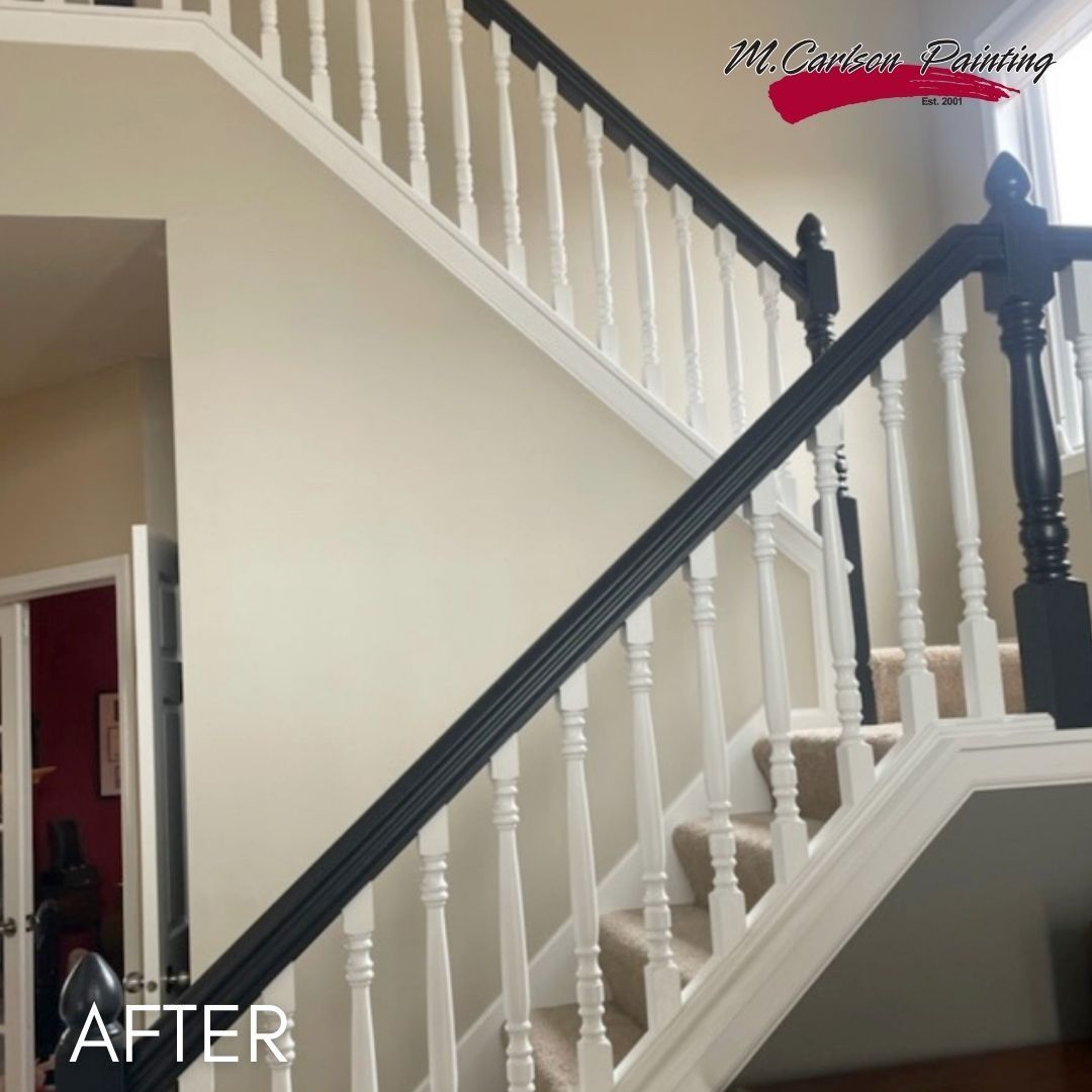 Staircase after painting, white balusters and risers below a dark handrail
