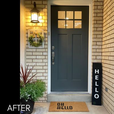 Front door painted dark slate gray, set in cream brick with a wreath beside it