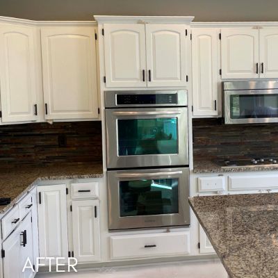 Excelsior kitchen after cabinet refinishing, white cabinets with black hardware around a double wall oven