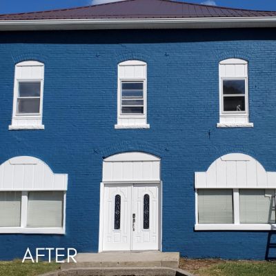 Brick commercial building painted deep blue with white window surrounds