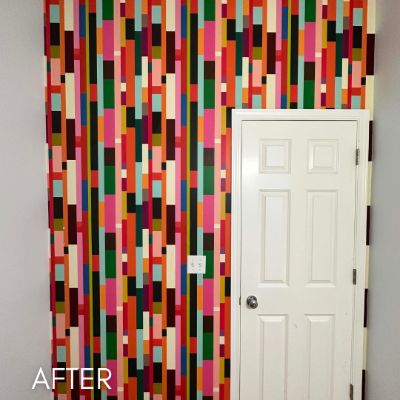 Hallway papered in a bold multicolored vertical pattern