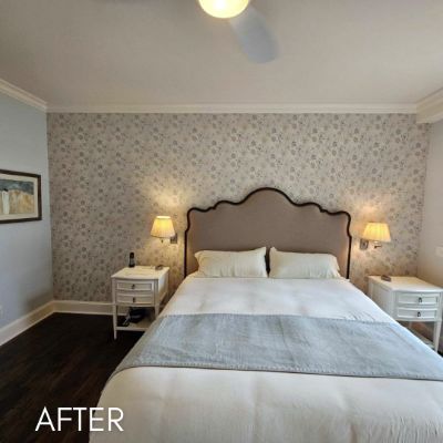 Bedroom papered in a soft floral print behind an upholstered headboard