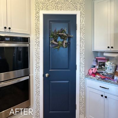 Kitchen papered in a cream print around a navy pantry door