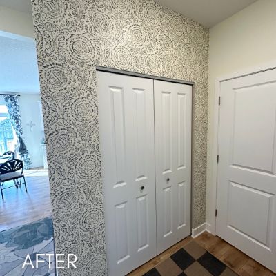 Hallway papered in a gray medallion print beside white closet doors