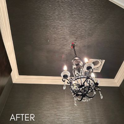 Dining room in dark grasscloth wallcovering below a crystal chandelier