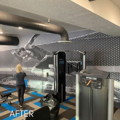 Gym interior with a photographic mural and hexagon-tiled wall behind the equipment