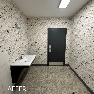 Restroom papered in a fine botanical print beside a dark door