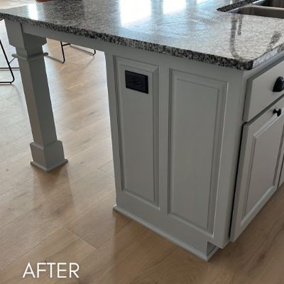 Kitchen island after refinishing in soft gray, under a granite top