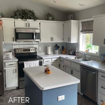 Kitchen after cabinet refinishing, white cabinets and a blue island