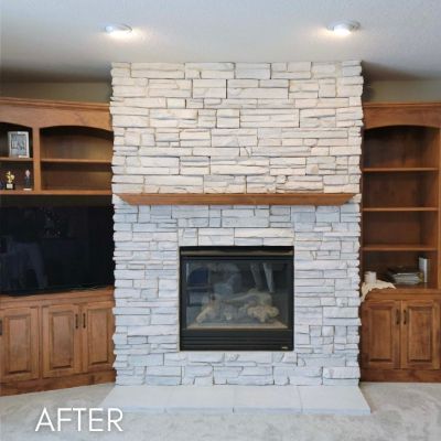 Stone fireplace whitewashed between wood built-in cabinets