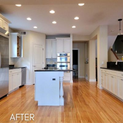 Kitchen after cabinet refinishing, white cabinets and island on oak flooring