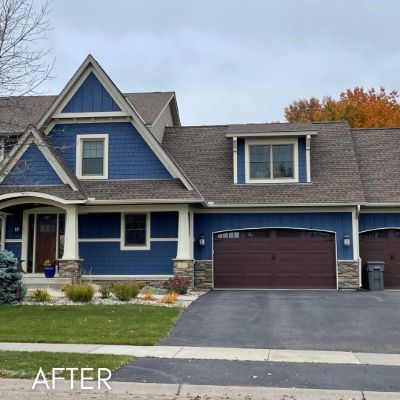 Two-story house in deep blue siding with cream trim and a brown garage door