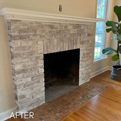 Stone fireplace whitewashed to a soft gray, beside a tall window