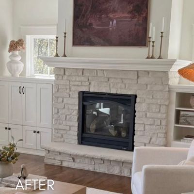 Whitewashed stone fireplace between white built-in cabinets