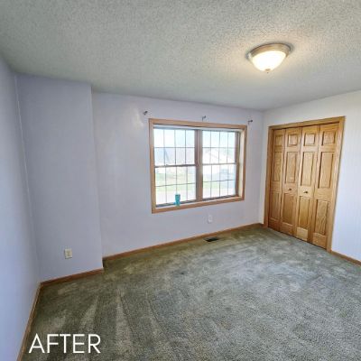 Empty bedroom after painting, pale blue walls beside a wood closet door
