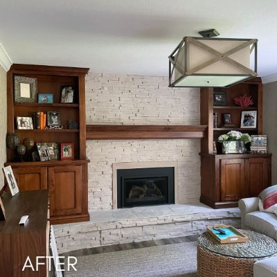 Stone fireplace whitewashed between dark wood built-in cabinets