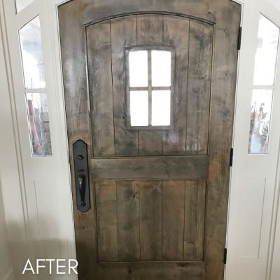 Arched wood front door with a glazed panel, between narrow sidelights