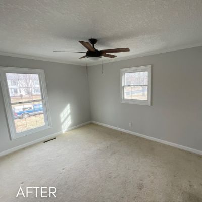 Empty bedroom after painting, soft gray walls between two windows