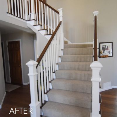 Staircase after painting, white balusters and newel posts beside a carpeted run