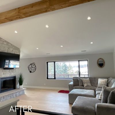 Living room after painting, white vaulted ceiling and an exposed beam above a stone fireplace