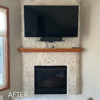 Stone fireplace after painting, with a wood mantel below a wall-mounted screen