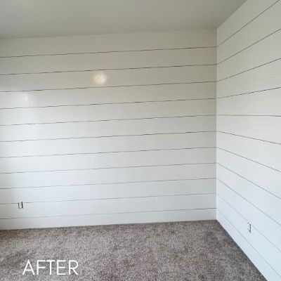 Room lined with white painted shiplap above gray carpet