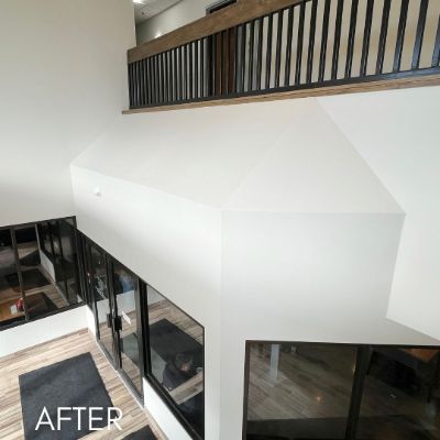 Vaulted stairwell painted white above a dark wood railing