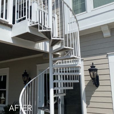 Exterior spiral staircase painted white against gray siding