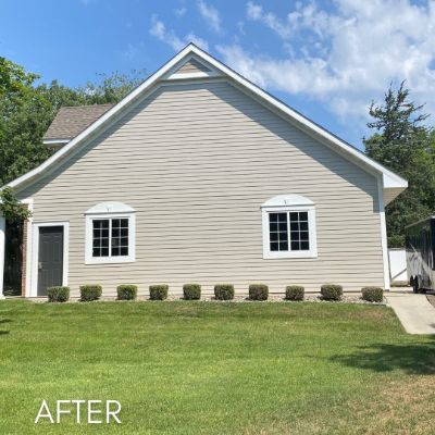 Gable end of a house in tan siding with white trimmed windows