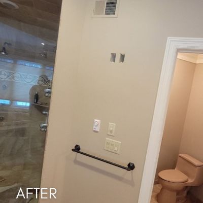 Bathroom after painting, pale walls beside a glass shower screen