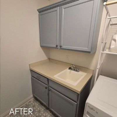 Laundry room cabinets refinished in soft gray above a utility sink