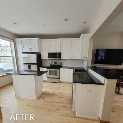 Kitchen after cabinet refinishing, white cabinets and black countertops