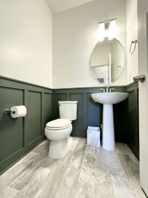 Powder room with dark green board and batten wainscoting below white walls