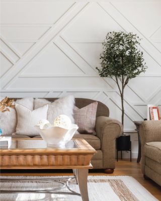 Living room with a white diagonal geometric trim accent wall behind a brown sofa