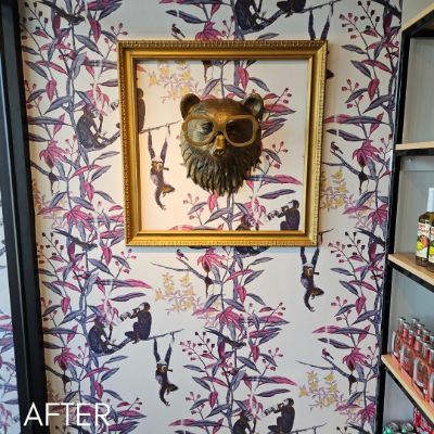 Shop wall papered in a pink and purple monkey print around a framed bear's head