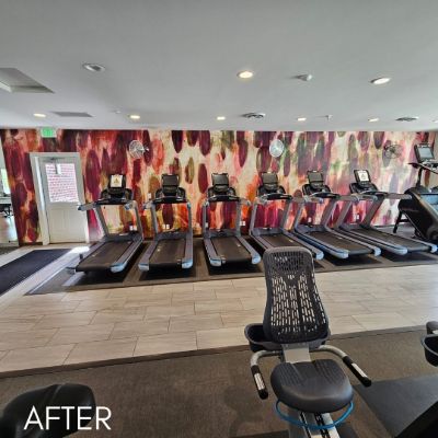 Gym interior with a painted flame mural behind a row of treadmills
