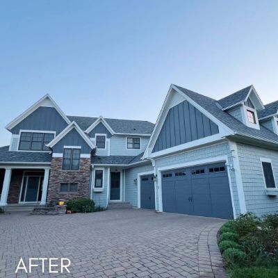 Two-story house in gray and white siding with a stone-faced garage