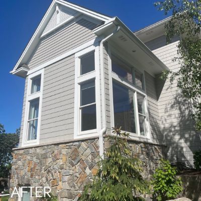 Bay window and gray siding above a stone foundation