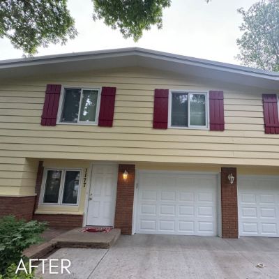 Split-level house in cream siding with deep red shutters