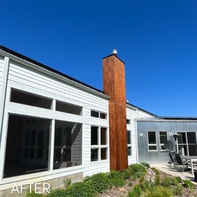 Single-story house in white siding with a stained cedar chimney surround