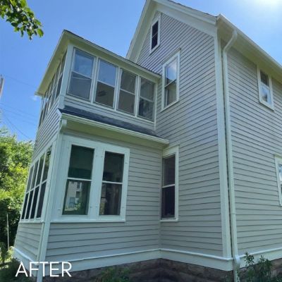 Three-story house in pale green siding with white window trim