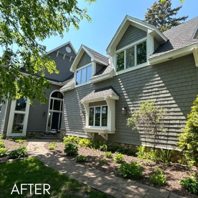 Large shingled house in warm gray with cream trim and dormer windows