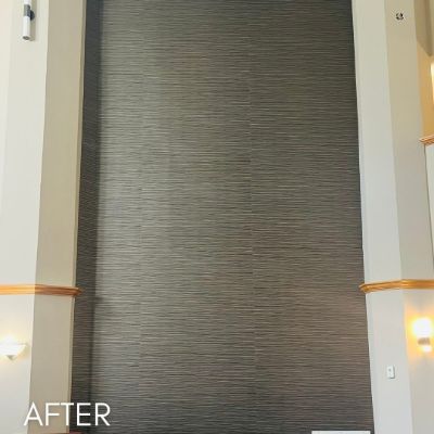Stairwell hung with a dark grasscloth wallcovering between wood rails