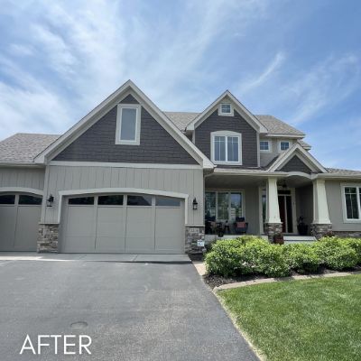 Two-story house in gray board and batten siding with a stone-faced garage
