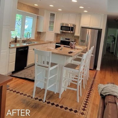 Kitchen after cabinet refinishing, white cabinets around a granite-topped island