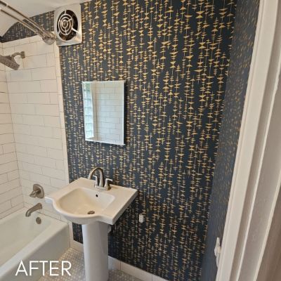 Bathroom papered in a navy and gold flecked print beside a tiled bath