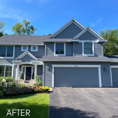Townhouses in slate blue siding with white trim and a paved driveway